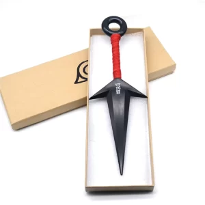 Kunai ninja con diseño negro y mango rojo, presentado en caja con símbolo de la Aldea de la Hoja.